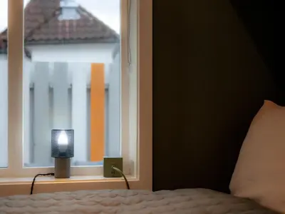 a bedroom with a bed and a window with a lamp at Modern Apartment in 1840-Building at Nordnes in Bergen