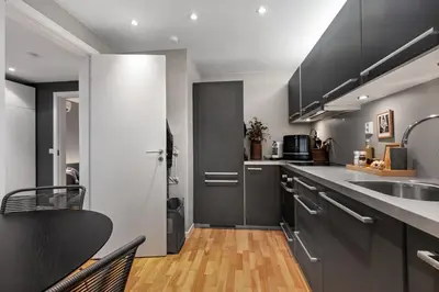 a kitchen with gray cabinets and a sink and a table at Modern Apartment in 1840-Building at Nordnes in Bergen