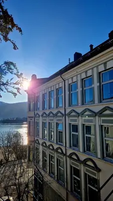 a building with the sun setting behind it at Jugend City Retreat - Ålesund Apartment in Ålesund