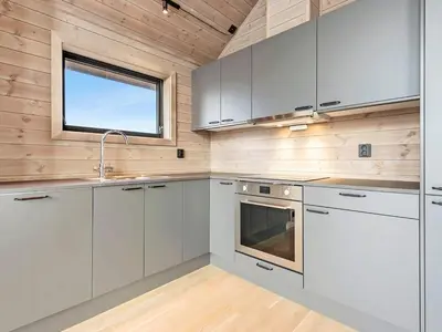 a kitchen with white cabinets and a window at 6 person holiday home in Averøya in Karvåg
