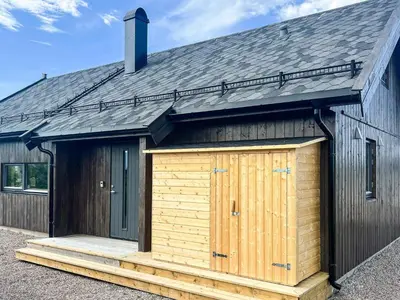 a large wooden shed with a black roof at 6 person holiday home in Averøya in Karvåg