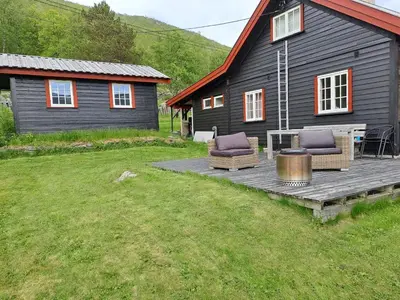 a wooden deck with two chairs and a house at Charming Cabin Near Hallingskarvet Ski Center, Cozy and Inviting! in Skoro