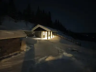 a building with lights in the snow at night at Bånseterlodgen in Favang