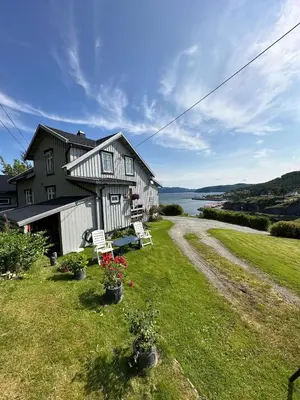 a house with a bench on the lawn next to a road at Kystperle med utsikt, lei en båt in Namsos