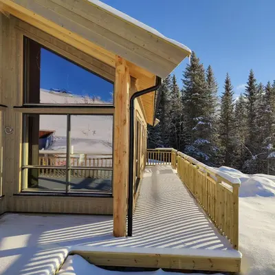 a wooden deck with a view of a house at Skogbrynet hytte in Svingvoll