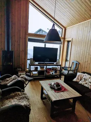 a living room with a tv and a table at Skogbrynet hytte in Svingvoll