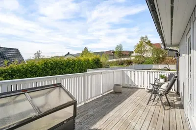 a wooden deck with a chair on a balcony at World Cup Trondheim 2025 in Trondheim