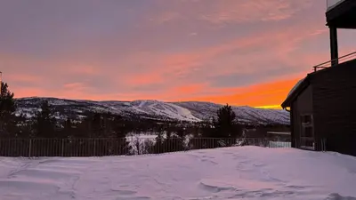 a snow covered yard with a sunset in the mountains at Exclusive and cozy apartment central Geilo area in Geilo