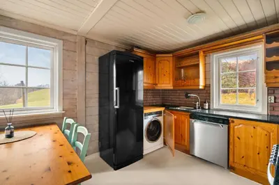 a kitchen with a black refrigerator and a table at Gildeskaal - A Fairytale Stay in Rosendal in Rosendal