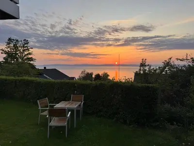 a table and chairs with the sunset in the background at Appartment with garden in Malvik