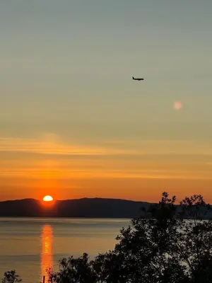 an airplane flying over the water at sunset at Appartment with garden in Malvik