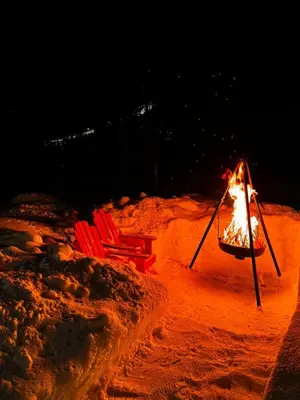 a fire pit and two chairs in the sand at night at Ustedalen Lodge in Geilo