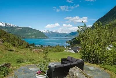 a couch sitting on a rock with a view of a lake at Huse Gjestegard in Kinsarvik