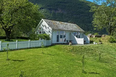a small white house with a fence in a yard at Huse Gjestegard in Kinsarvik