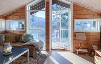 a living room with a couch and large windows at Cozy Home In Stryn With Sauna in Stryn