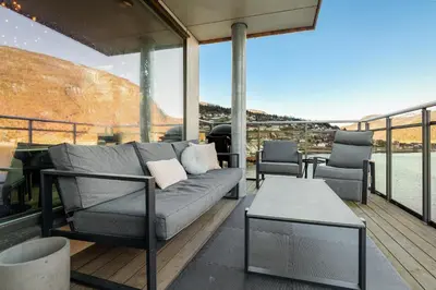 a living room with a couch and chairs on a deck at Penthouse with fjord view and parking in Sogndal