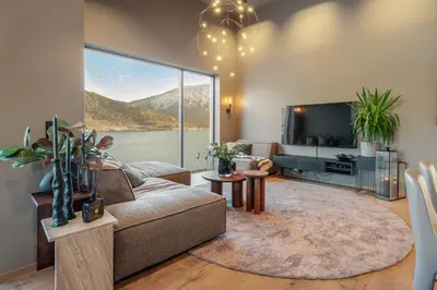 a living room with a couch and a tv at Penthouse with fjord view and parking in Sogndal
