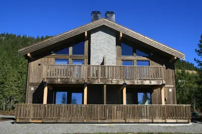 a large wooden house with a balcony at Sjusjøen Hytteutleie AS in Sjusjøen