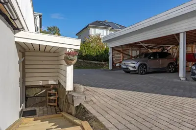 a house with a car parked in a parking lot at Bright and nice downtown apartment in Lillehammer