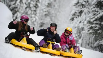 three people are riding on a snowmobile in the snow at Bright and nice downtown apartment in Lillehammer