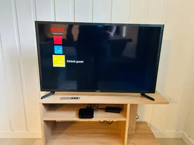 a flat screen tv sitting on a wooden stand at Bright and nice downtown apartment in Lillehammer