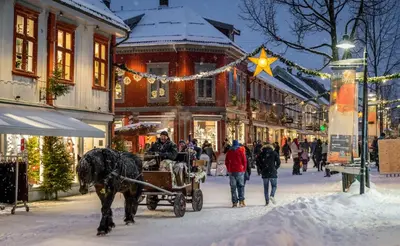 a horse drawn carriage on a snowy street with people at Central apartment - Free parking and Wi-Fi in Lillehammer