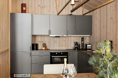 a kitchen with stainless steel appliances and a table with wine glasses at Premium Cabin By Kvitfjell Ski Slopes in Ringebu