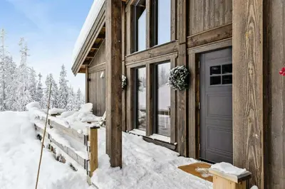 a wooden cabin with a door in the snow at Premium Cabin By Kvitfjell Ski Slopes in Ringebu