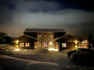 a house with lights on in the snow at night at Architect-Designed Mountain Cabin At Mosetertoppen in Øyer