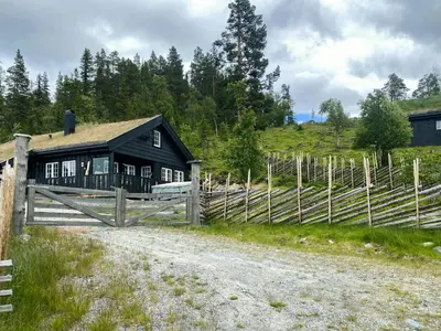a black barn with a wooden fence next to a dirt road at Mountain Cabin With Views Over Nesfjellet in Nesbyen