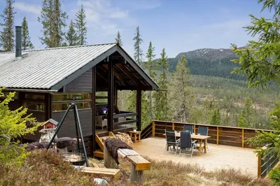 a cabin with a deck with a table and chairs at Close To Nature In Ål Cabin At Haglebu in Eggedal