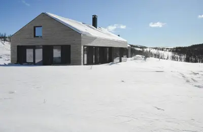 a building in a snow covered field with a house at Cabin Overlooking Hallingskarvet National Park in Geilo