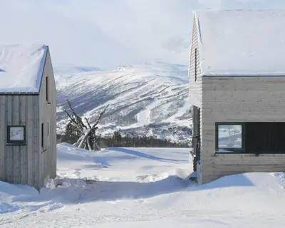 a building in the snow with mountains in the background at Cabin Overlooking Hallingskarvet National Park in Geilo