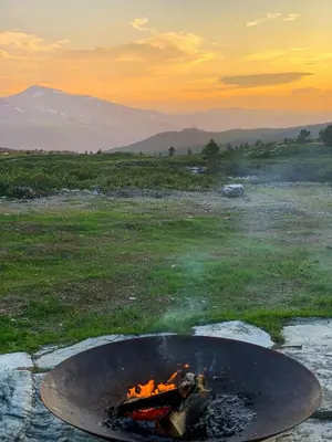 a fire pit in a field at sunset at Architect Drawn Holiday Home Near Rondane Park in Høvringen