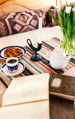 an open book on a table with a candle and a cup of coffee at Architect Drawn Holiday Home Near Rondane Park in Høvringen