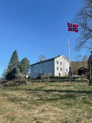 a flag on a pole in front of a building at Historic Old Rectory In The Heart Of Norway in Vestre Gausdal
