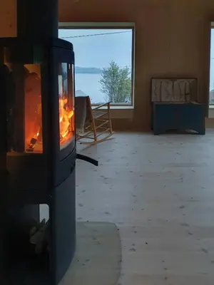 a fireplace in a room with a view of the ocean at Architect-Designed Cabin With Beach Nearby in Lensvik