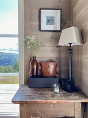 a table with a lamp and a vase on it at Traditional Cabin With Views Of Hardangervidda in Uvdal