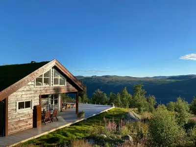 a cabin with a deck and mountains in the background at Traditional Cabin With Views Of Hardangervidda in Uvdal