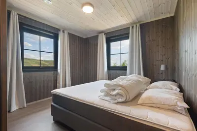 a bed in a bedroom with two windows at Trysil turistesenter hytte in Trysil