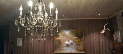 a chandelier hanging from a wall with a painting at Trysil turistesenter hytte in Trysil