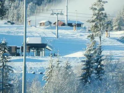a snow covered field with a ski lift in the distance at Trysil turistesenter liten leilighet in Trysil