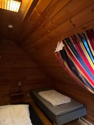 a room with a bed in a wooden cabin at Cozy Oceanfront Escape in Nautnes