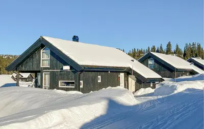 a house covered in snow with a pile of snow at Cozy Home In Sjusjøen With Sauna in Sjusjøen