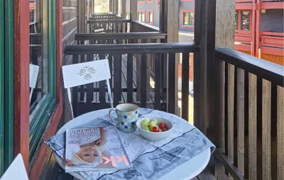 a table with a newspaper and a bowl of fruit on a balcony at 5 Bedroom Cozy Apartment In Ustaoset in Ustaoset