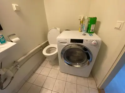 a bathroom with a washing machine and a toilet at Central appartment with a nice view in Bergen