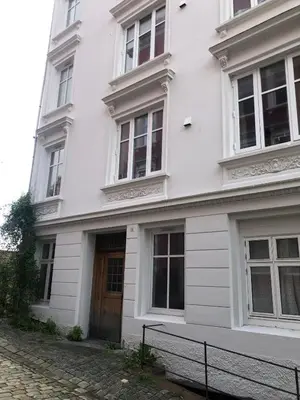 a white building with a wooden door and windows at Central appartment with a nice view in Bergen