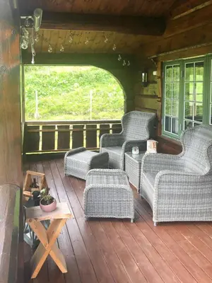 a porch with wicker chairs and a table on a deck at Charming Log Cabin In Jøldalen in Rennebu