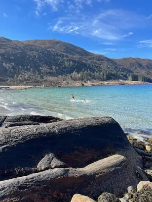 a person swimming in a body of water at Apartment by the fjord, with boat and jacuzzi included in Larsnes