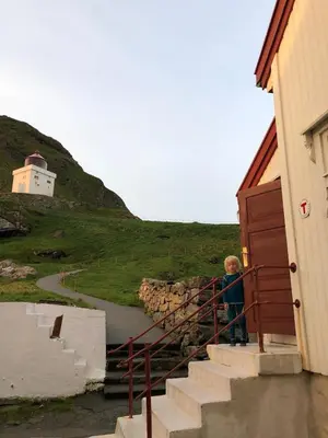 a boy standing on the stairs of a building at Apartment by the fjord, with boat and jacuzzi included in Larsnes